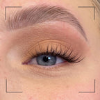 Close-up of an eye with long, dark eyelashes and well-groomed eyebrow.