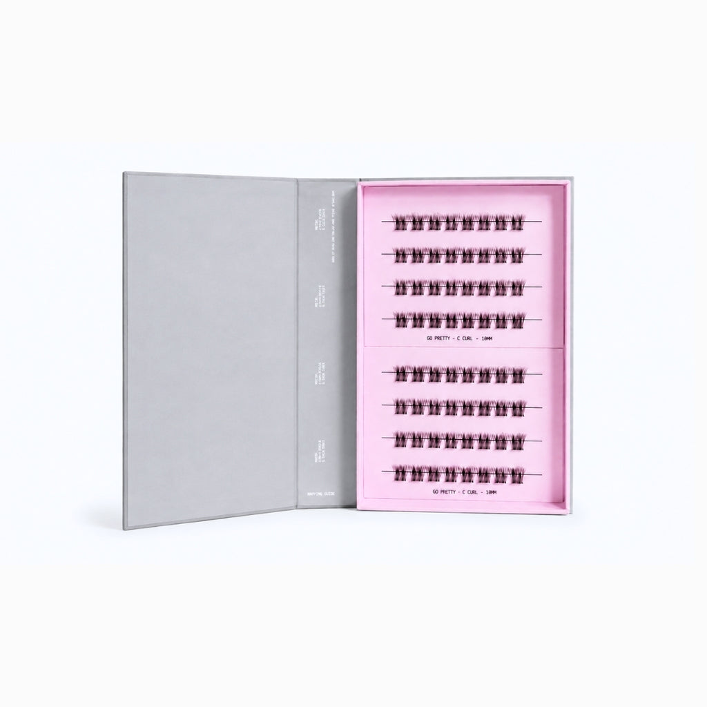 An open gray presentation box showing a pink interior tray with multiple rows of black false eyelashes arranged neatly.